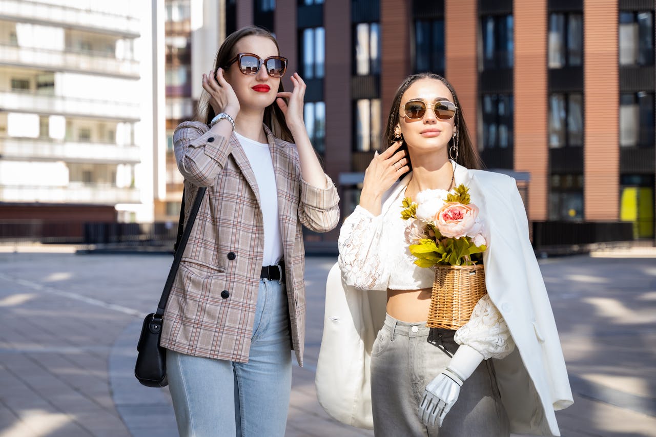 services-02 Two stylish women enjoy a sunny day in the city wearing chic outfits and sunglasses.